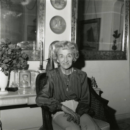 Elderly woman sits inside her home