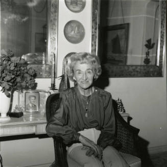 Elderly woman sits inside her home