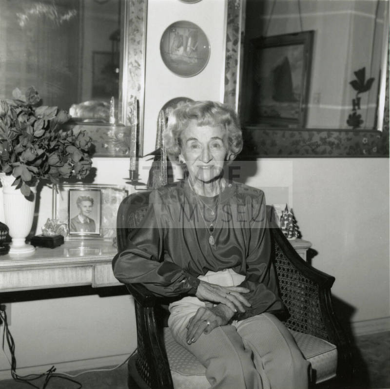 Elderly woman sits inside her home