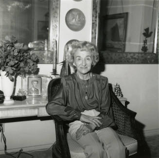 Elderly woman sits inside her home