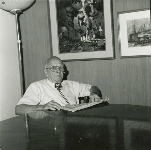 Elderly man with newspaper at dining table