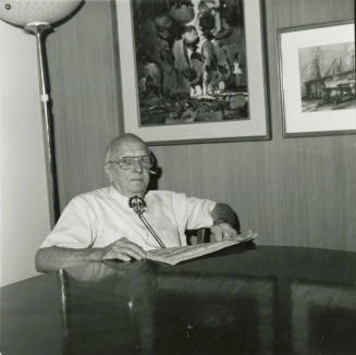 Elderly man with newspaper at dining table