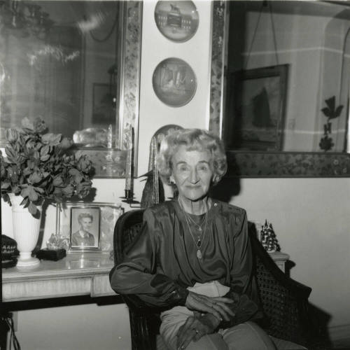 Elderly woman sits inside her home