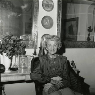 Elderly woman sits inside her home