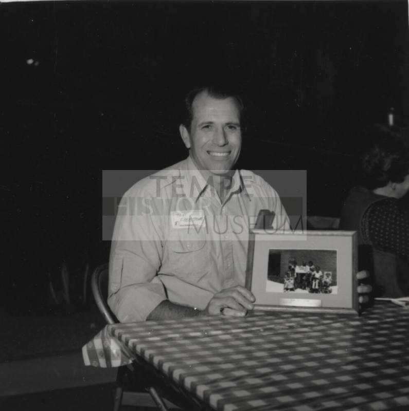 Tom Freestone poses at table with a picture frame
