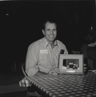 Tom Freestone poses at table with a picture frame