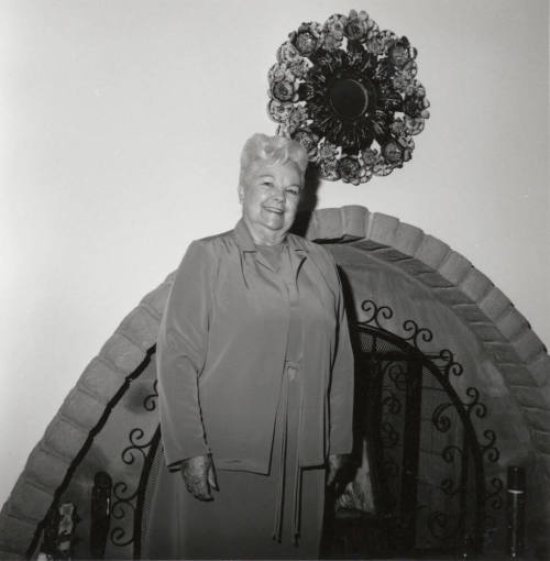 Unidentified Woman standing in front of Fireplace