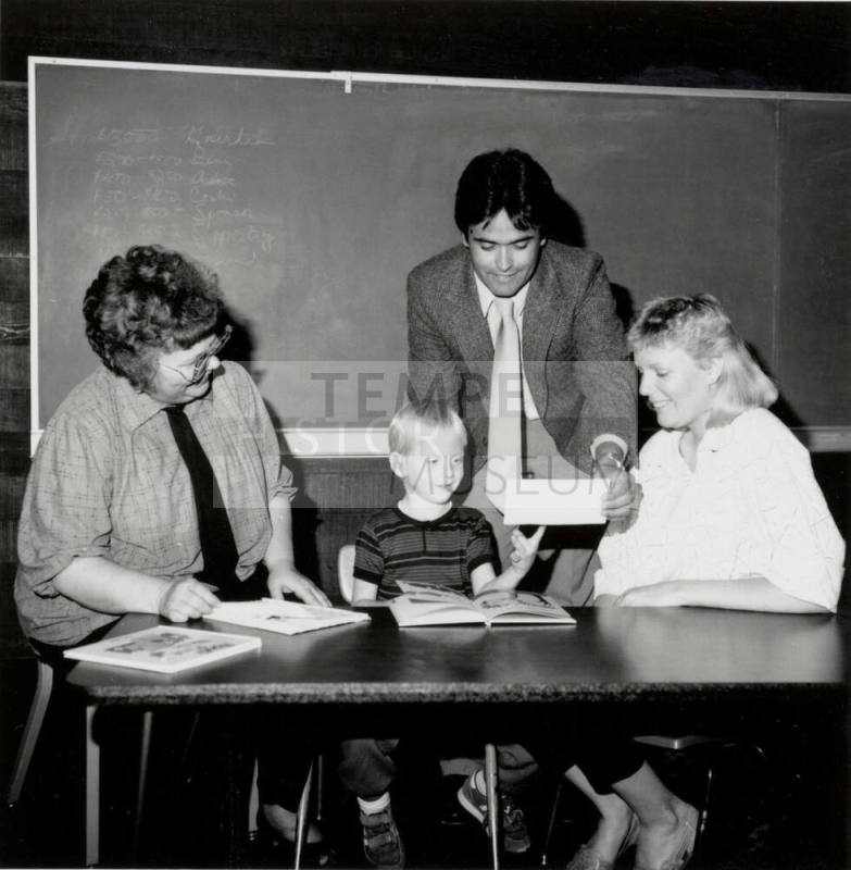 Unidentified Group of Adults around a table with a young boy