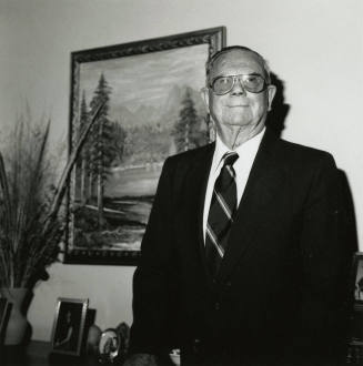 Uknown Man Standing in Front of Landscape Painting