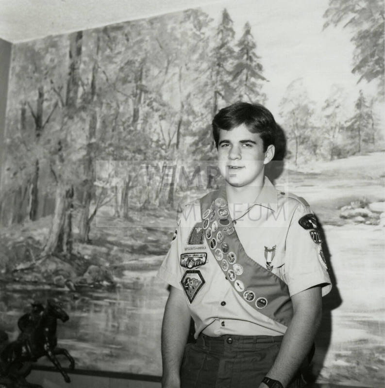 Boy Scout standing in front of a landscape mural