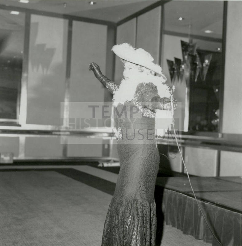 A costumed woman in lace dress and featherd hat performs at a United Way event.