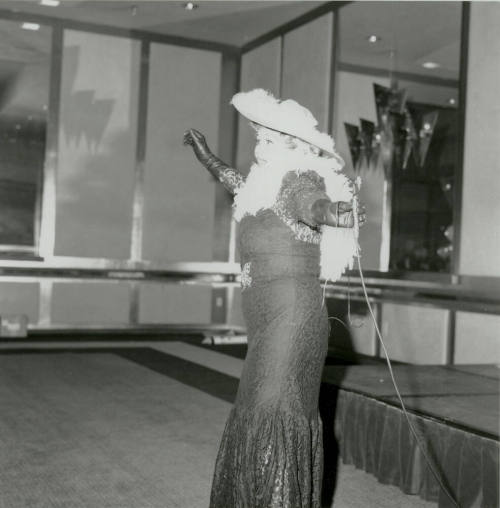 A costumed woman in lace dress and featherd hat performs at a United Way event.