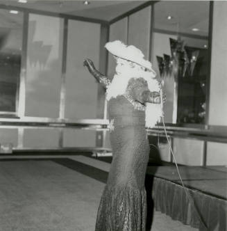 A costumed woman in lace dress and featherd hat performs at a United Way event.