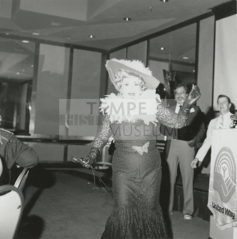 A costumed woman in lace dress and featherd hat performs at a United Way event.
