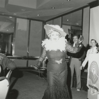 A costumed woman in lace dress and featherd hat performs at a United Way event.