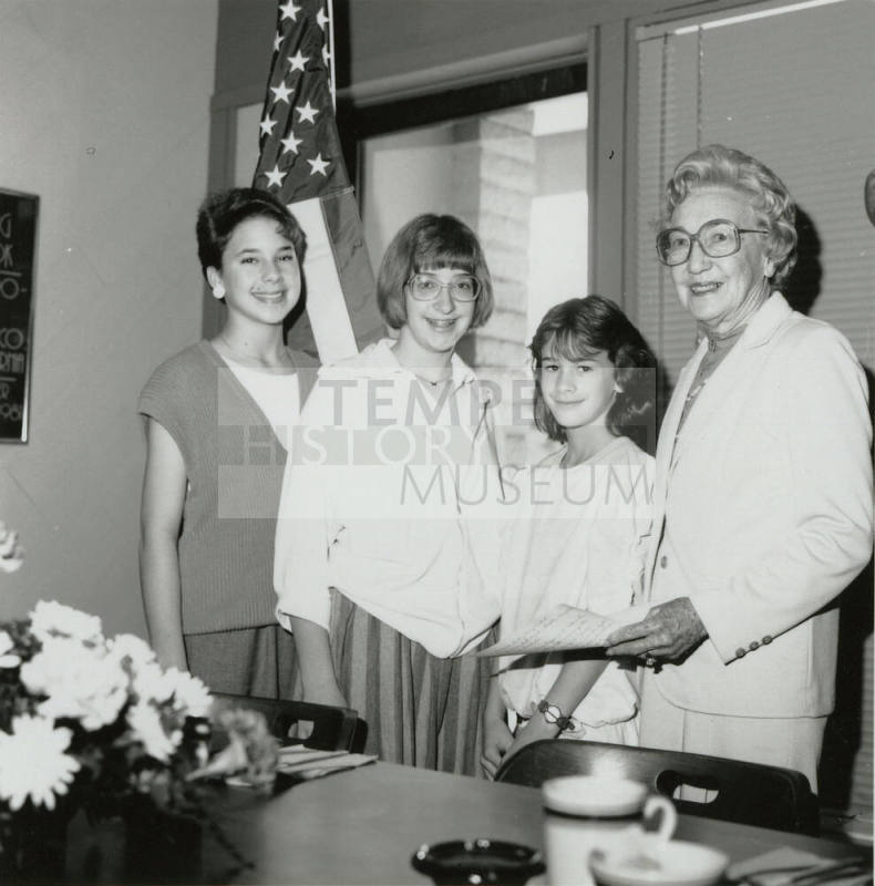 Four Females stand in front of a U.S. Flag