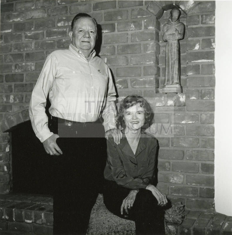 Middle-aged couple in front of fireplace with Saint Francis statue