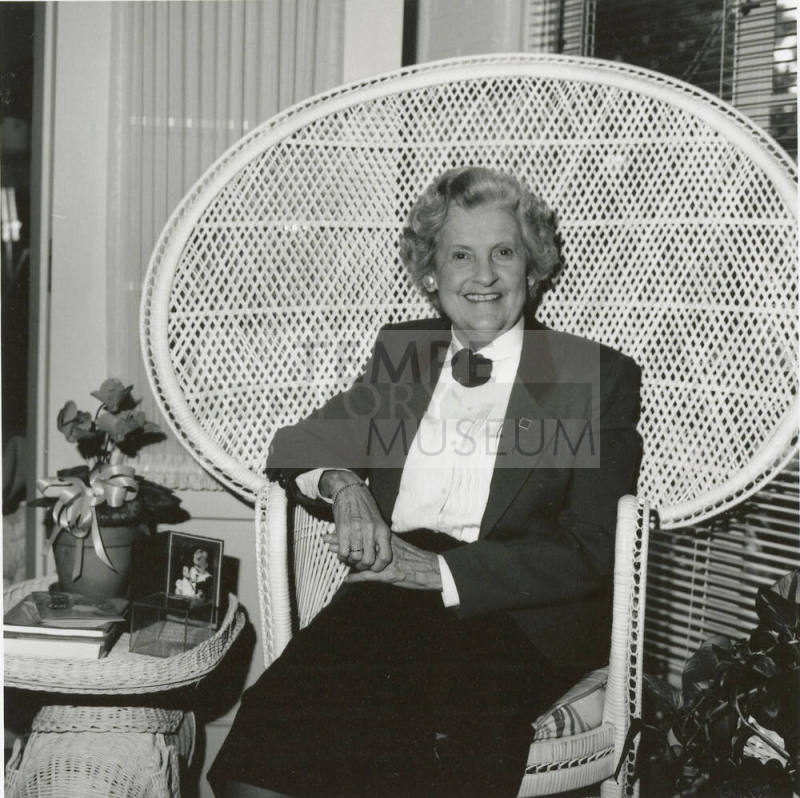 Older woman sits in living room in woven chair