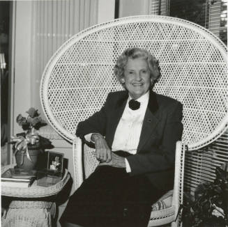 Older woman sits in living room in woven chair