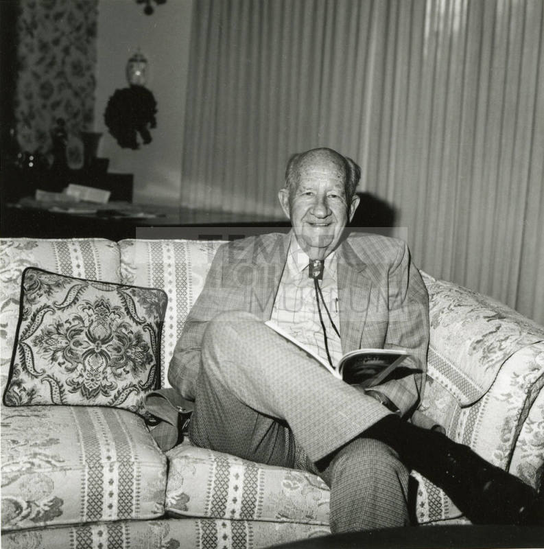 Older man sits on sofa in living room