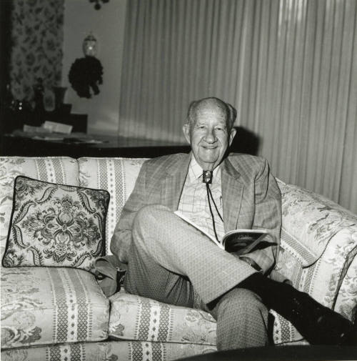 Older man sits on sofa in living room