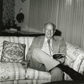 Older man sits on sofa in living room
