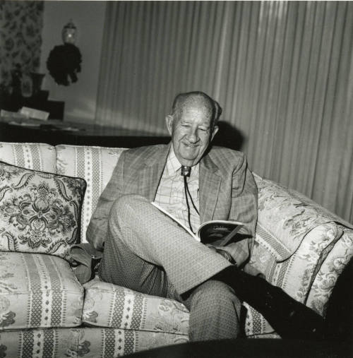 Older man sits on sofa in living room
