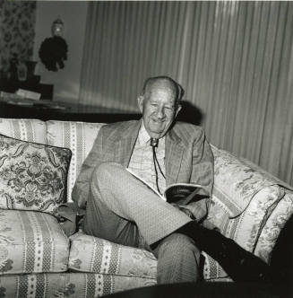 Older man sits on sofa in living room