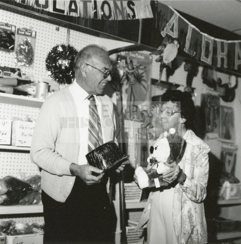 Older man and older woman in a thrift store showing their finds