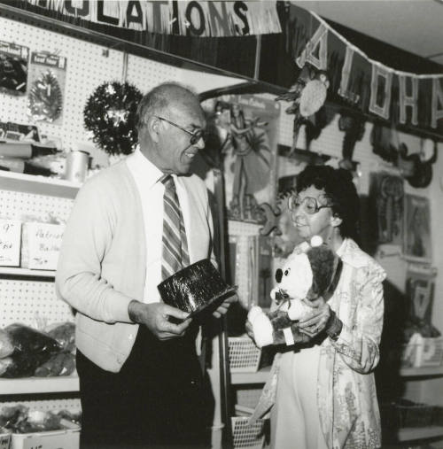 Older man and older woman in a thrift store showing their finds