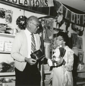 Older man and older woman in a thrift store showing their finds