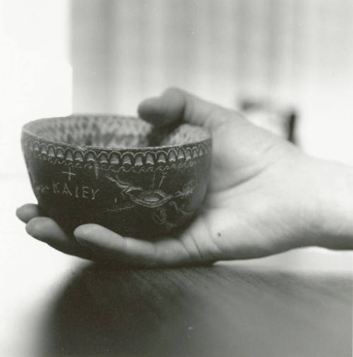 Hand holds small ceramic bowl reading "KAlEY"