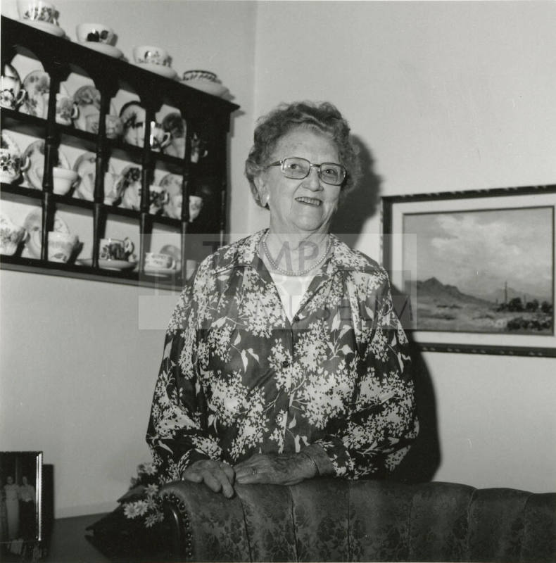 Older woman in living room with painting and china cabinet
