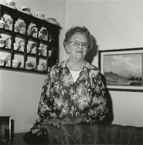 Older woman in living room with painting and china cabinet