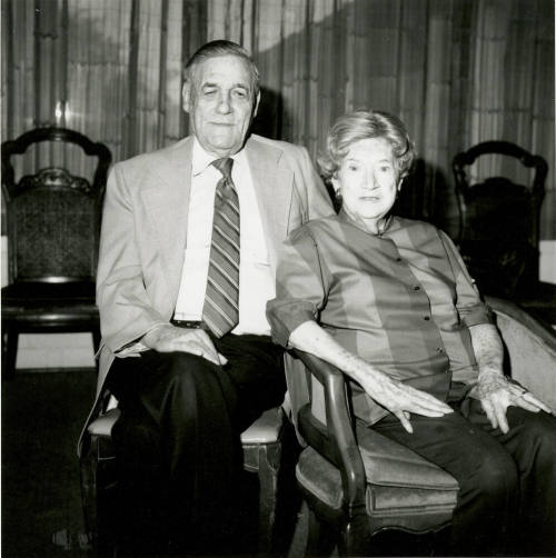 Seated older couple surrounded by chairs