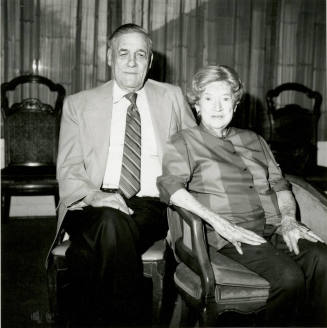 Seated older couple surrounded by chairs