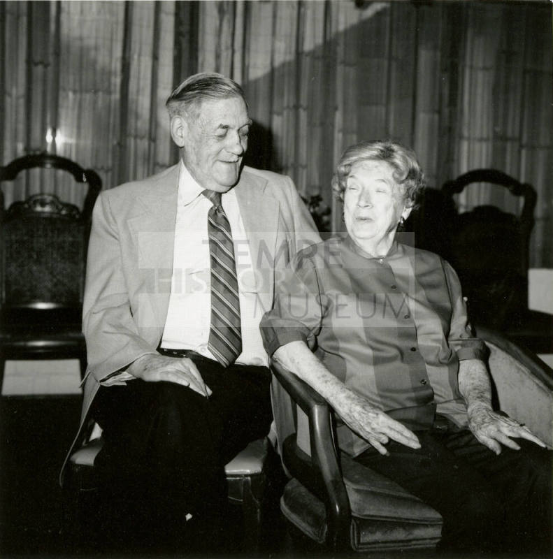 Seated older couple surrounded by chairs