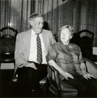 Seated older couple surrounded by chairs