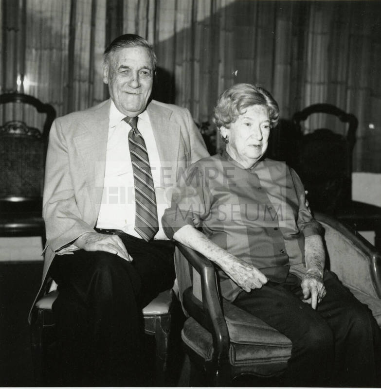 Seated older couple surrounded by chairs