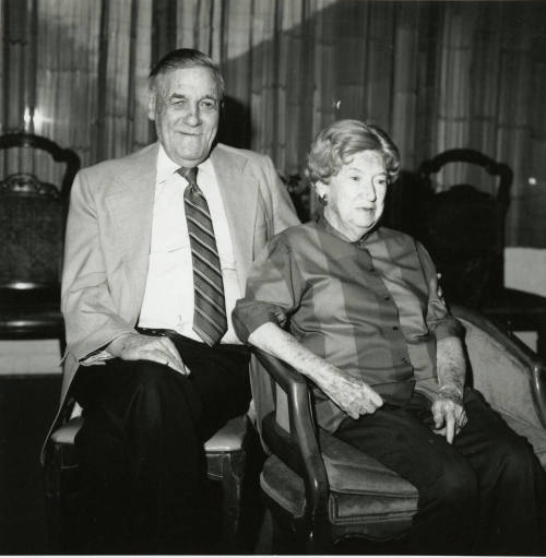 Seated older couple surrounded by chairs