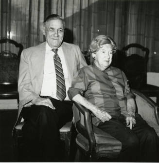 Seated older couple surrounded by chairs