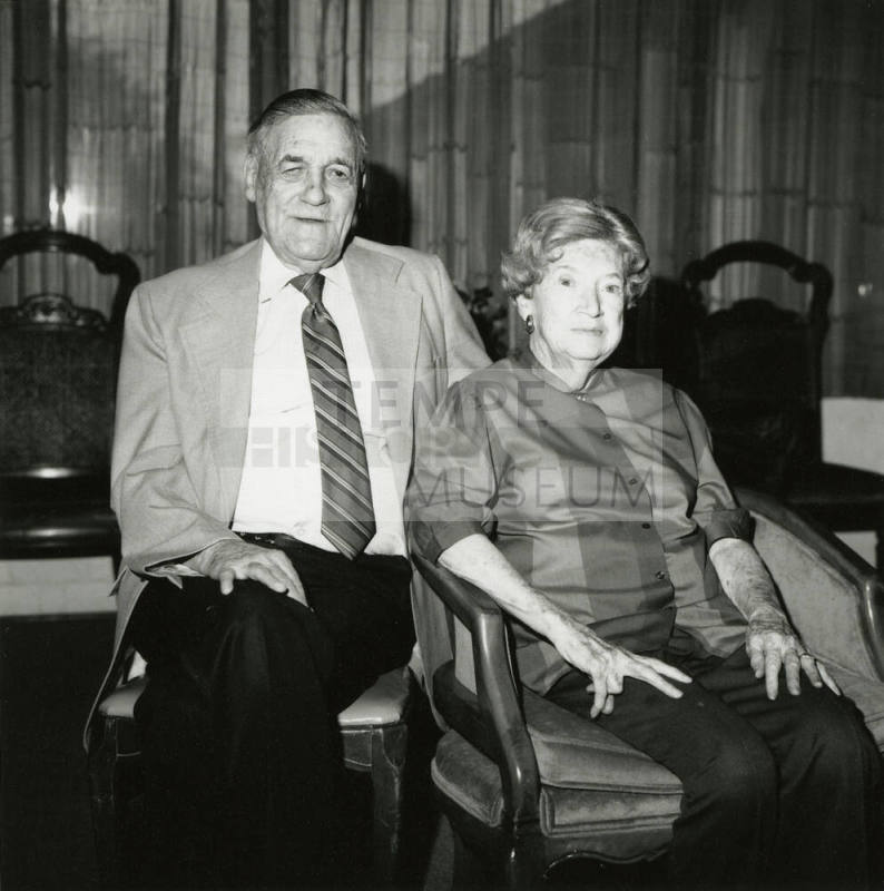 Seated older couple surrounded by chairs