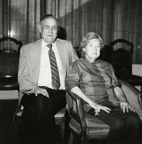 Seated older couple surrounded by chairs