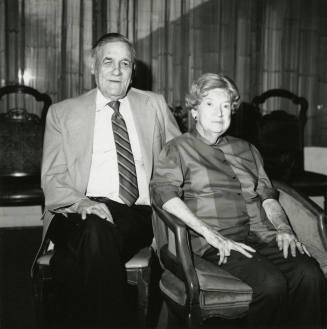Seated older couple surrounded by chairs