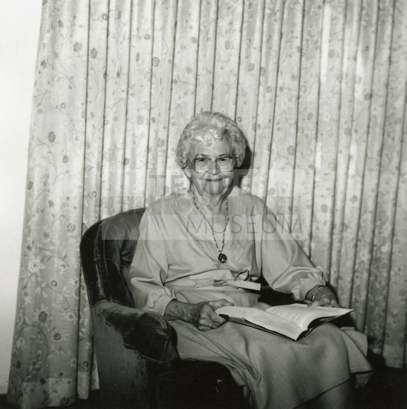 Unidentified Gray-Haired Woman Sits in Chair with Book