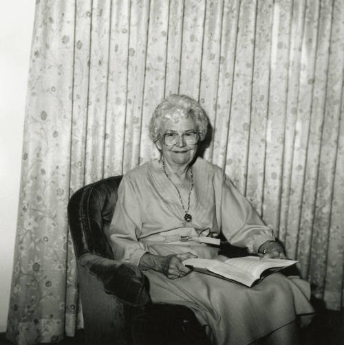 Unidentified Gray-Haired Woman Sits in Chair with Book