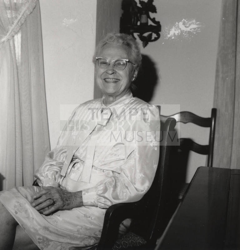 Unidentified Older woman sits in a chair in her home