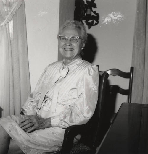 Unidentified Older woman sits in a chair in her home