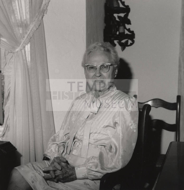 Unidentified Older woman sits in a chair in her home