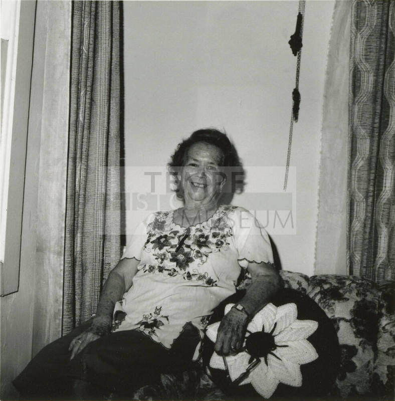 Unidentified woman sits on couch & poses for camera (1 of 2)